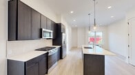 Located at 487 Market St in Saddle Brook, NJ, this thoughtfully designed two-bedroom, one-bathroom residence offers a clean, contemporary aesthetic throughout. Light-toned hardwood flooring runs seamlessly across the entire unit, complementing the bright white walls and creating a cohesive, airy feel.

The open-concept kitchen and living area serves as the heart of the home. The kitchen is outfitted with dark espresso cabinetry that extends to the ceiling for generous storage, crisp white quartz countertops, a full suite of stainless steel appliances including a gas range, over-the-range microwave, and French door refrigerator, and a large center island with a built-in sink. Globe pendant lights hang above the island, adding a modern finishing touch.

Both bedrooms are comfortably sized, filled with natural light from large windows that offer neighborhood views. Each room features recessed lighting and dedicated closet space, with the primary bedroom benefiting from a spacious double-door closet. In total, the unit includes three closets, providing excellent storage throughout.

The bathroom is finished with large-format beige tile, a marble-topped vanity with a fluted wood base, and safety grab bars. A dedicated laundry area adds everyday convenience, rounding out this well-appointed, move-in-ready residence.