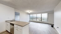Located along Marine Drive in North Vancouver, this two-bedroom, two-bathroom residence offers a well-organized layout designed to maximize both comfort and functionality. The open-concept living, dining, and kitchen area forms the heart of the home, bathed in natural light streaming through expansive floor-to-ceiling windows. A private balcony extends from the main living space, providing unobstructed views of the surrounding mountains and North Vancouver cityscape below.

The kitchen features white cabinetry, a peninsula with a built-in sink and counter seating, stainless steel appliances including a refrigerator and electric range, and a practical layout that integrates seamlessly with the dining and living areas. Light wood-tone flooring flows consistently throughout the unit, complemented by white walls and textured ceilings.

Both bedrooms are generously proportioned, with large windows framing picturesque mountain views and ample closet storage, including louvred built-in closets. The primary bedroom benefits from direct access to a well-appointed bathroom. A second full bathroom serves the remainder of the unit, featuring a tub-shower combination, white cabinetry, and a granite-style countertop. A hallway with additional closets and storage completes the thoughtful floor plan.