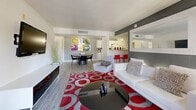 Located at 3900 E Sunset Rd in Las Vegas, NV, this 2-bedroom, 2-bathroom residence offers a well-designed single-floor layout that balances comfort and functionality. The open-concept living and dining area is a visual centerpiece, highlighted by wood-look flooring, a bold accent wall in charcoal gray, and a large sliding glass door that invites natural light and provides access to an outdoor patio with greenery views. The kitchen features white cabinetry with granite-style countertops, a full suite of white appliances including a gas range, and direct access to the in-unit laundry room, which includes overhead storage cabinets. The primary bedroom is a comfortable retreat with a dedicated closet and room for a seating area. The second bedroom benefits from a bright window, blue accent wall, and wood-look flooring. Both bathrooms are finished with white tile surrounds, tub-shower combinations, granite-style vanity countertops, and wood-look flooring. Two closets provide ample storage throughout the unit. The overall aesthetic is clean and modern, combining neutral tones with thoughtful design details throughout.