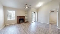 Located in Albuquerque, NM, this well-appointed 2-bedroom, 2-bathroom single-floor residence offers a thoughtfully designed layout with a mix of light wood-style flooring and plush carpeting throughout. The open living room is a standout space, anchored by a classic brick fireplace with a raised hearth, built-in shelving, and vaulted ceilings that lend an airy, spacious feel. A ceiling fan overhead and a sliding glass door leading to a private balcony complete the inviting atmosphere. The semi-open kitchen is separated from the living area by a half-wall breakfast bar, and features stainless steel appliances, white cabinetry, and recessed lighting. A pantry provides additional storage. Both bedrooms are carpeted and include ceiling fans and closets, with the primary bedroom offering a generous walk-in closet with built-in shelving. Two full bathrooms each include a tub/shower combination. A connecting hallway links the bedrooms and bathrooms, adding to the functional flow of the floor plan. Natural light filters through multiple windows and the balcony door, contributing to the bright, neutral aesthetic of the home. The layout makes efficient and comfortable use of every square foot available.