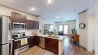 This well-appointed one-bedroom, one-bathroom residence in Rockwall, Texas offers a smart, efficient layout across a single floor. The open-concept kitchen and living area serves as the heart of the home, where rich dark cabinetry, granite countertops, and a full suite of stainless steel appliances — including a refrigerator, range, and microwave — define the kitchen. A peninsula with bar seating provides additional dining space and separates the kitchen from the living area. Wood-look flooring runs throughout the main living spaces, adding warmth and continuity. The living room is bright and inviting, featuring crown molding, recessed lighting, a ceiling fan, and French doors that open to an outdoor balcony with neighborhood views. The spacious primary bedroom is finished with plush carpet, a ceiling fan, and a large window that brings in generous natural light. The bathroom continues the design cohesion with dark wood cabinetry, granite countertops, and wood-look flooring, complemented by an open linen closet with built-in shelving for ample storage. A dedicated closet and hallway complete the layout, making this residence a well-rounded and functional living space in a desirable Texas community.