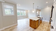 Located at 525 Ridge St, Unit 307 in Charlottesville, VA, this thoughtfully designed 2-bedroom, 2-bathroom unit offers a clean, contemporary aesthetic with high-quality finishes throughout. Light wood-tone flooring flows seamlessly across the entire space, complementing the soft neutral walls and crisp white trim.

The kitchen serves as a true centerpiece, featuring dark cabinetry with gold hardware, a stainless steel appliance suite, a stainless range hood, subway tile backsplash, and a generous island with a warm wood base and white quartz countertop, illuminated by two globe pendant lights. The open living area benefits from an abundance of natural light through large windows and a private balcony door.

The primary bedroom offers comfortable proportions and includes a sliding barn door, a double closet, and convenient access to an in-unit laundry closet with a full washer and dryer. The second bedroom features a ceiling fan and bright windows with outdoor views. Both bathrooms are finished with modern floating vanities, white quartz countertops, warm wood cabinetry, and matte black fixtures. The primary bath includes a frameless glass walk-in shower with white subway tile and a hexagonal mosaic niche. A gold-framed mirror accents the second bath's vanity, adding a refined touch.