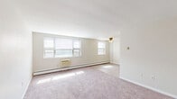 Located at 7801 Algon Ave in Philadelphia's 19111 zip code, this two-bedroom, one-bathroom residence is thoughtfully arranged on a single floor. The layout flows efficiently between living areas, bedrooms, and utility spaces, as revealed by the 3D floor plan overview.

The main living area is bright and open, featuring wall-to-wall carpeting in neutral tones, multiple windows that invite generous natural light, a ceiling fan, and baseboard heating supplemented by a wall-mounted air conditioning unit. The clean, white walls and simple trim work give the space a fresh, move-in-ready appearance.

The generously sized primary bedroom continues the carpeted flooring and is equipped with a built-in closet, a wall A/C unit, and a large window for ample daylight. The second bedroom also offers comfortable proportions with carpeting, neutral walls, and its own window, making it suitable as a guest room, home office, or additional sleeping quarters.

The bathroom is a standout feature, finished with classic white and blue ceramic tile — accented with vertical blue tile strips in the tub surround — offering a retro aesthetic that adds character to the space. A full bathtub and overhead ventilation complete the room.

An entry area with a closet provides convenient storage upon arrival. Overall, the residence presents a clean, functional, and well-lit living environment.