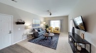 This single-floor residence offers a thoughtfully designed layout with cohesive modern finishes throughout. The kitchen is outfitted with dark espresso cabinetry, white countertops, stainless steel appliances including a range and over-the-range microwave, and a double basin sink — providing ample workspace and storage. The open living area features wood-look flooring, a ceiling fan, and large windows that invite natural light, creating a bright and comfortable gathering space. A dedicated dining area with hardwood-style flooring offers an intimate setting for meals. Two well-sized bedrooms are finished with plush carpet, ceiling fans, and windows. The primary bedroom includes a walk-in closet and an en-suite bathroom, while the second bedroom is served by a full hall bathroom. Both bathrooms feature dark vanity cabinetry, white countertops, large mirrors, and modern lighting fixtures. One bathroom includes a shower-tub combination. Neutral gray walls and consistent trim work tie the entire space together, delivering a clean, contemporary aesthetic throughout every room.