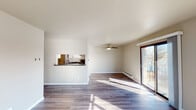 This single-floor unit in Green Bay, Wisconsin offers a well-organized layout with two bedrooms, one full bathroom, and an open living and kitchen area. Throughout the space, wood-style plank flooring in a warm medium tone creates a cohesive and contemporary look, complemented by neutral gray-beige walls and clean white trim.

The living area is generously proportioned, filled with natural light from a large sliding glass door that opens to an outdoor patio. An additional window further brightens the space, and a ceiling fan provides year-round comfort. A baseboard heating system runs along the exterior walls. The kitchen is partially open to the living area via a pass-through window, and features white cabinetry with matte black hardware, dark laminate countertops, and stainless steel appliances including a range with an overhead ventilation hood.

Both bedrooms are well-sized, each offering natural light through standard windows with outdoor views and baseboard heating. The full bathroom includes a tub-shower combination, a vanity with granite-style countertop, white cabinetry, matte black fixtures, and wood-style flooring. An adjacent linen closet with built-in shelving adds practical storage to the space.