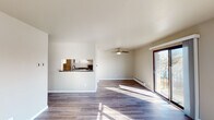 This single-floor unit in Green Bay, Wisconsin offers a well-organized layout with two bedrooms, one full bathroom, and an open living and kitchen area. Throughout the space, wood-style plank flooring in a warm medium tone creates a cohesive and contemporary look, complemented by neutral gray-beige walls and clean white trim.

The living area is generously proportioned, filled with natural light from a large sliding glass door that opens to an outdoor patio. An additional window further brightens the space, and a ceiling fan provides year-round comfort. A baseboard heating system runs along the exterior walls. The kitchen is partially open to the living area via a pass-through window, and features white cabinetry with matte black hardware, dark laminate countertops, and stainless steel appliances including a range with an overhead ventilation hood.

Both bedrooms are well-sized, each offering natural light through standard windows with outdoor views and baseboard heating. The full bathroom includes a tub-shower combination, a vanity with granite-style countertop, white cabinetry, matte black fixtures, and wood-style flooring. An adjacent linen closet with built-in shelving adds practical storage to the space.