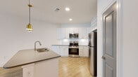 Located at 1105 Sunset Crest Lane in Summerville, SC, this well-appointed one-bedroom, one-bathroom residence offers a thoughtfully designed single-floor layout with contemporary finishes throughout. Light wood-tone flooring flows seamlessly across every room, creating a bright and cohesive aesthetic.

The open-concept kitchen and living area serves as the heart of the home. The kitchen is outfitted with crisp white cabinetry accented by gold hardware, a subway tile backsplash, quartz-style countertops, and a full suite of stainless steel appliances including a range, over-the-range microwave, and French door refrigerator. A central island with an undermount sink and stylish pendant lighting adds both function and visual appeal, while an upper wine rack adds a distinctive touch.

The living area is generously proportioned, featuring recessed lighting, a ceiling fan with a gold-accented fixture, and large windows that invite an abundance of natural light and outdoor views.

The spacious primary bedroom continues the light and airy theme, with corner windows, a ceiling fan, and ample room to furnish comfortably. A dedicated walk-in closet with wire shelving provides excellent storage capacity.

The bathroom features a tub-shower combination with marble-style tile surround, white cabinetry with gold hardware, and a framed mirror, maintaining the modern and cohesive design language found throughout the home.