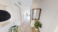 Located on the 9th floor of McPherson Square NE in Calgary, Alberta, this one-bedroom, one-bathroom unit offers a well-planned layout with modern finishes throughout. Light wood-tone flooring runs continuously through the space, complementing the crisp white walls and creating a clean, cohesive aesthetic.

The entryway features a built-in sliding storage closet and leads down a bright corridor into the open-concept kitchen and living area. The kitchen is equipped with full-height white cabinetry, a classic white subway tile backsplash, light quartz countertops, and a complete suite of stainless steel appliances including a refrigerator, dishwasher, electric range, and over-the-range microwave. Track lighting overhead ensures the kitchen is well-lit. A dining area sits adjacent, benefiting from a large window with open city views.

The living room is anchored by an exposed concrete column accent wall, adding an industrial architectural touch to the otherwise minimalist space. Large windows flood the room with natural light and frame views of the surrounding Calgary skyline.

The bedroom is a cozy, well-proportioned retreat with a high clerestory window and a large built-in wardrobe providing ample storage. The bathroom features a full soaker tub with white subway tile surround, a vanity with white countertop, and light wood-look flooring.