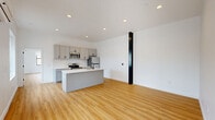 Located at 933 McGee Street in the heart of Kansas City, Missouri, this modern one-bedroom, one-bathroom unit offers a thoughtfully designed open-concept layout. Light hardwood flooring runs throughout, creating a warm and cohesive feel across every room.

The kitchen and living area flow seamlessly together, anchored by a sleek kitchen island with a white quartz countertop and matte black faucet. Gray shaker-style cabinetry lines the walls, complemented by a white subway tile backsplash and a full suite of stainless steel appliances, including a range, microwave, and refrigerator. A window above the kitchen brings in natural light and city views.

The living area is bright and open, featuring large windows that frame views of the surrounding Kansas City skyline. A ceiling fan and a wall-mounted mini-split unit provide year-round climate control, while recessed lighting adds to the clean, modern aesthetic.

The spacious primary bedroom offers ample room and is accessible through sliding mirrored closet doors, with additional natural light from its own window. An in-unit stacked washer and dryer adds everyday convenience.

The bathroom is finished with floor-to-ceiling glossy subway tile, a walk-in shower enclosed by a sleek black-framed sliding glass door, and hardwood flooring that continues the unit's cohesive design language.