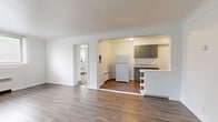 Located at 425 W Bancroft Street in Toledo, Ohio, this 2-bedroom, 1-bathroom unit offers a practical and comfortable single-floor layout. The open living area features light-toned hardwood-style flooring and bright white walls, creating a clean and airy atmosphere. Natural light filters in through windows fitted with horizontal blinds, enhancing the sense of space throughout.

The kitchen is connected to the living area via a charming arched passageway and features gray cabinetry, white appliances including a refrigerator and range, light countertops, and a small breakfast bar with built-in shelving — a functional and efficient cooking space. The living room is spacious and open, with baseboard heating units providing warmth.

Both bedrooms are carpeted for comfort, each offering windows with outdoor views and baseboard heating. The primary bedroom is generously sized and includes its own closet. The second bedroom is well-proportioned with its own closet and window. Additional hallway spaces provide practical flow between rooms.

The bathroom includes a full tub and shower combination with classic cream and black tile detailing, maintaining a timeless character. With two dedicated closets and well-connected hallways, this unit offers efficient and livable space in a straightforward, functional design.