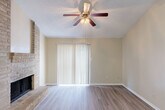 Located in Spring, TX, this single-story 2-bedroom, 2-bathroom home offers a well-organized layout designed for functional everyday living. The living room serves as the heart of the home, featuring a striking floor-to-ceiling brick fireplace, wood-look laminate flooring, a ceiling fan, and a large sliding glass door with vertical blinds that allow natural light to fill the space. The galley-style kitchen is efficiently designed with white cabinetry, laminate countertops, a double sink, and black appliances including a range and refrigerator. The wood-look flooring continues through the kitchen, which opens directly into the living area. Both bedrooms are carpeted and finished with warm neutral tones, ceiling fans, and windows that bring in natural light. The primary bedroom benefits from vaulted ceilings and direct access to its own bathroom, which features white cabinetry and a tub-shower combination. A second full bathroom, also equipped with a tub-shower combo and built-in wall niches, serves the secondary bedroom and guests. A connecting hallway links the bedrooms and bathrooms, keeping the layout cohesive. Throughout the home, neutral beige walls, textured ceilings, and consistent finishes create a clean, comfortable ambiance.