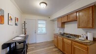 Located at 40 Windwood Courts in Buffalo, NY, this two-story home offers a practical and comfortable layout across two floors. The main level features a bright kitchen equipped with warm honey-toned wood cabinetry, granite-style countertops, a double stainless steel sink, and durable light hardwood flooring. Crown molding adds a refined touch throughout, and a exterior-facing window and door bring in natural light. The adjacent living room is carpeted and inviting, with windows overlooking the outdoors and enough space to accommodate a full seating arrangement. Upstairs, two carpeted bedrooms provide comfortable retreats. The primary bedroom includes closet storage and connects to a hallway that leads to the shared bathroom. The second bedroom, also carpeted with a window, offers a cozy and well-lit space. The full bathroom is clean and bright, featuring a shower-tub combination, a white vanity with mirror, and a frosted privacy window. Additional utility space and a staircase connecting the floors round out the home's layout. Crown molding details and neutral wall tones throughout give the home a cohesive, well-maintained appearance.