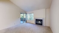 This single-story residence in Driftwood, California offers a thoughtfully laid-out floor plan with two bedrooms and two bathrooms. The living room serves as the centerpiece of the home, distinguished by soaring vaulted ceilings that lend an open, airy quality to the space. A tile-surround fireplace anchors one wall, providing a classic focal point, while a large picture window and sliding glass door flood the room with natural light and frame views of surrounding mature trees. The sliding door opens directly onto a private balcony, extending the living space outdoors.

The kitchen features white cabinetry, dark countertops, a double stainless steel sink, and a window that brings in additional natural light. Both bedrooms are carpeted and well-proportioned, with one bedroom offering its own sliding glass door and balcony access overlooking the wooded scenery. The bathrooms are clean and functional, each featuring a tub-shower combination, wood-look flooring, and a window for ventilation. Neutral tones and plush carpeting throughout the main living areas contribute to a calm, cohesive ambiance across the entire home.