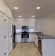 This contemporary 1-bedroom apartment in Lacey, Washington, offers 670 square feet of efficiently designed living space. The open-concept floor plan maximizes the use of space, creating a seamless flow between the living area and kitchen. The kitchen is a standout feature, boasting sleek white cabinetry, stainless steel appliances, and a generous island with a sink, providing both additional counter space and a casual dining area. Light wood-look flooring throughout the main living areas adds warmth and continuity.

The bedroom, measuring 130 square feet, features plush carpeting and a large window, ensuring ample natural light. The bathroom is modern and well-appointed with a spacious vanity, large mirror, and stylish fixtures. Convenience is key in this apartment, with an in-unit washer and dryer tucked away in a dedicated laundry area.

Recessed lighting and strategically placed fixtures provide excellent illumination throughout the space. The living room features vertical blinds over a large window or sliding door, suggesting possible outdoor access. Overall, this apartment combines contemporary design with practical amenities, creating an ideal living space for singles or couples seeking a modern, low-maintenance home.