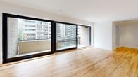 Located in the heart of downtown Montréal on Rue Drummond, this well-appointed 2-bedroom, 2-bathroom residence offers a thoughtfully designed single-level layout with a clean, modern aesthetic throughout. Warm honey-toned hardwood flooring flows through the living areas and bedrooms, complemented by crisp white walls and recessed lighting that create a bright, inviting atmosphere.

The two living areas provide flexible spaces for lounging or entertaining, while the dedicated kitchen is efficiently laid out in a U-shape with white cabinetry, stainless steel appliances including a built-in microwave and dishwasher, grey countertops, and a window that brings in natural light. Both bedrooms are generously proportioned, featuring built-in sliding closets. The primary bedroom is notably spacious, with large floor-to-ceiling sliding doors opening to the private balcony.

The balcony offers open views of Montréal's dynamic downtown skyline, surrounded by mid- and high-rise buildings. The two bathrooms are finished in contrasting styles — one features all-white large-format tiles with a soaking tub for a clean, minimalist look, while the second is clad in warm grey tiles with a modern vanity and bathtub. Two hallways connect the spaces efficiently. Recessed lighting throughout adds a polished, contemporary finish to this centrally located urban residence.