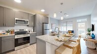 This 1-bedroom, 1-bathroom unit in Rochester, MN offers a thoughtfully designed layout that maximizes its compact footprint. The open-concept kitchen flows seamlessly into the living area, creating an efficient and welcoming shared space. The kitchen is outfitted with grey shaker-style cabinetry, granite countertops, a subway tile backsplash, stainless steel appliances, and a peninsula island with bar seating and pendant lighting overhead. Light wood-tone flooring runs throughout the main living areas, enhancing the bright, airy feel. The living room features large windows and a glass-paneled door that invite generous natural light and provide outdoor views. The bedroom offers a cozy retreat with plush carpeting, a bold teal accent wall, and a sizable window with exterior views. The full bathroom is clean and functional, featuring a soaking tub and shower combination with brushed nickel fixtures and wood-look tile flooring. A dedicated closet provides practical storage. The unit's neutral color palette, modern fixtures, and consistent design language create a cohesive and comfortable living environment throughout.
