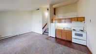 Located at 7342 W Marine Dr in Milwaukee, Wisconsin, this single-floor unit offers a straightforward and functional layout. The open living area features soft carpeting underfoot, creating a comfortable and inviting atmosphere. A staircase visible from the main living space adds architectural interest, while the open sight lines between the living area and kitchen make the space feel connected and cohesive.

The kitchen is equipped with warm wood-tone cabinetry, light laminate countertops, a stainless steel single-basin sink, and a white electric range with coil burners. Upper and lower cabinet storage provides ample space for kitchen essentials, and the layout is compact yet efficient.

The bedroom is a calm, well-lit room with plush carpet, white walls, and a large window fitted with vertical blinds that allows natural light to filter in while offering views of the surrounding greenery. Baseboard heating runs along the walls, ensuring warmth throughout the cooler months.

The bathroom is clean and utilitarian, featuring a full tub and shower combination with built-in shelving, a toilet, and a towel bar. The all-white finish gives the space a simple, tidy appearance.

Overall, this unit presents a practical and livable space in a residential Milwaukee neighborhood, suitable for those seeking a no-frills, functional home.