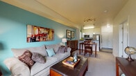 This single-floor residence at 1580 Milwaukee Way in Missoula offers a thoughtfully designed open-concept layout that seamlessly connects the living, dining, and kitchen areas. The living room is anchored by a signature teal accent wall, plush carpet flooring, and a large window that fills the space with natural light and outdoor views of the surrounding greenery. Track lighting and pendant fixtures provide warm, layered illumination throughout the common areas.

The kitchen is well-equipped with stainless steel appliances, including a refrigerator and range, dark countertops, crisp white cabinetry, and rich hardwood-style flooring. A peninsula with a built-in sink and breakfast bar creates a natural transition into the dining area, which features its own pendant lighting and teal accent wall.

The bedroom offers a calm retreat with a soft green accent wall, plush carpet, a generous closet, and a window overlooking the neighborhood. The bathroom includes a wide vanity with dark countertops, white cabinetry, tile flooring, and a full tub-shower combination. A dedicated in-unit laundry area with a stacked washer and dryer adds everyday convenience. Throughout the residence, clean white trim, consistent finishes, and a cohesive color palette create a polished, move-in-ready atmosphere.