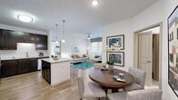 This single-floor residence offers a thoughtfully designed open-concept layout that seamlessly connects the kitchen, dining, and living areas. The kitchen is a standout feature, showcasing rich dark cabinetry, granite countertops, a classic white subway tile backsplash, stainless steel appliances, and a central island with pendant lighting — ideal for both cooking and casual dining. Light wood-style flooring flows throughout the main living areas, enhancing the bright and airy atmosphere created by abundant natural light from multiple windows.

The living room is a comfortable and welcoming space, complete with a ceiling fan and large windows that invite natural light and outdoor views. The dining area accommodates a round table and seating, positioned conveniently adjacent to the kitchen.

Both bedrooms are generously sized, each featuring plush carpeting, ceiling fans, and large windows. The primary bedroom includes an en-suite bathroom with a granite-topped vanity, dark cabinetry, tile flooring, and a walk-in shower, as well as access to a walk-in closet. The secondary bathroom offers a similar vanity design paired with a soaking tub and shower combination. A dedicated in-unit laundry area provides added everyday convenience, completing this well-rounded and functional residence.