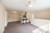Located at 11086 Windsong Cir in Naples, FL, this two-story residence offers 2 bedrooms and 2 bathrooms across a thoughtfully laid-out floor plan. The main level hosts the primary living spaces, where a combined living and dining area provides a comfortable, open feel. Warm neutral tones and plush carpeting carry throughout, complemented by ceiling fans and textured ceilings. The kitchen features speckled stone countertops, a double stainless steel sink, white cabinetry, and a breakfast bar that connects seamlessly to the dining area. Both bathrooms are finished with stone-look tile flooring, white vanities with generous mirrors, and tub/shower combinations. The bedrooms are carpeted and bright, each benefiting from natural light through slatted windows and ceiling fans overhead. The primary bedroom is a comfortable size with its own closet, while a second well-proportioned bedroom provides flexibility for guests or a home office. A dedicated in-unit laundry room with washer hookup and built-in shelving adds everyday convenience. A staircase connects the levels, and a utility room rounds out the functional layout. This Naples residence offers a practical and comfortable living environment in a well-established community.