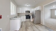 Located at 4015 Covington Hwy in Decatur, GA, this single-floor unit offers three bedrooms, one bathroom, a kitchen, a hallway, and three closets within a compact and efficiently arranged floor plan. The kitchen is a standout feature, showcasing white shaker-style cabinetry, granite-look countertops, a stainless steel refrigerator, range, and microwave, all set atop light wood-look flooring that adds brightness to the space. A window above the sink allows natural light to fill the room. Each of the three bedrooms is finished with neutral-toned carpet and ceiling fans, creating a comfortable and consistent feel throughout. The spacious primary bedroom includes a dedicated closet with louvered doors. Additional bedrooms feature windows with outdoor views of surrounding greenery. The bathroom is finished with clean white subway tile surrounding a full soaking tub, complemented by a window for natural ventilation. Neutral warm-gray walls are consistent throughout the unit, giving the space a cohesive and move-in-ready appearance. A central hallway connects all rooms, providing a logical and practical layout. The unit includes multiple closets for ample storage.