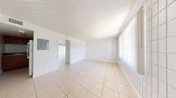 Located in Tampa, FL, this two-bedroom, one-bathroom unit offers a practical and efficiently designed single-floor layout. Light-toned ceramic tile flooring runs consistently throughout the space, creating a cohesive and easy-to-maintain interior. The living area is bright and open, featuring a distinctive white square-tile accent wall and large windows dressed with vertical blinds that allow generous natural light to filter in. A textured ceiling adds subtle character to the main living space.

The kitchen is compact yet functional, equipped with rich wood-toned cabinetry, dark stone-look countertops, a built-in range, and full-size refrigerator. The white tile wall detailing continues here, maintaining a consistent design thread throughout the unit.

The primary bedroom is generously sized and includes a sliding-door closet with a built-in rod for ample storage. The second bedroom mirrors the clean, minimal aesthetic of the rest of the unit, with the same tile flooring and white walls. The bathroom features a full-size soaking tub with shower, all finished in crisp white surfaces for a clean, utilitarian look.

A wall-mounted electrical panel is conveniently accessible from the main living area. Overall, this unit presents a clean, bright, and straightforward living space well-suited for comfortable everyday living in Tampa.