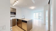 Located at 320 Tweedsmuir Ave in Toronto's Forest Hill neighbourhood, this well-appointed one-bedroom, one-bathroom unit offers a thoughtfully designed open-concept layout across a single floor. Light hardwood flooring flows throughout, complementing the bright, neutral palette and creating a cohesive, modern aesthetic.

The combined kitchen and living area forms the heart of the unit. The kitchen is outfitted with rich dark wood cabinetry, stainless steel appliances including a full-size refrigerator and range, a tiled backsplash, and a central island with a light stone countertop and undermount sink — ideal for both cooking and casual dining. Track lighting above the island adds a refined finishing touch.

The living area benefits from expansive floor-to-ceiling windows that frame views of the surrounding Toronto cityscape and greenery, flooding the space with natural light throughout the day.

The bedroom is a comfortable and private retreat, featuring a mirrored sliding closet and its own large window with open city views. The bathroom is clean and functional, with dark tile flooring, white subway-tiled walls, a decorative tile accent border, and a full soaker tub with overhead shower. This unit offers an efficient, modern living experience in a vibrant Toronto neighbourhood.