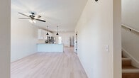 This two-story home on Bost Drive in Fort Smith, Arkansas, offers a clean, modern aesthetic characterized by neutral tones, light wood-look flooring, and black hardware accents that carry consistently throughout the space. The main floor hosts an open-concept kitchen and living area that together form the heart of the home. The kitchen is well-appointed with white shaker-style cabinetry, granite countertops, stainless steel appliances including a range, microwave, refrigerator, and dishwasher, and a peninsula with pendant lighting overhead. A ceiling fan serves the adjacent living area, which receives natural light through a front-facing window. The main floor also provides access to the exterior via a door with a sidelight panel.

The upper floor accommodates all three bedrooms, two full bathrooms, a hallway, and two closets. The primary bedroom is a comfortable size with a ceiling fan and a window offering neighborhood views. The bathrooms are finished with white cabinetry, granite countertops, dual undermount sinks, round mirrors, and black fixtures. A private water closet adds separation within the bathroom layout. Closets feature built-in shelving and hanging rods, maximizing storage efficiency throughout the home.