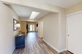 Located at 21495 LeMay Dr in Riverside, CA, this generously sized single-story home offers a well-designed layout across three bedrooms, two bathrooms, and a variety of functional living spaces. The entryway immediately impresses with its vaulted ceiling and skylight, flooding the foyer with natural light while setting an open, welcoming tone. Warm hardwood-style flooring flows throughout the home, providing visual continuity from room to room. The living room serves as a central gathering point, anchored by a classic fireplace flanked by windows and a set of French doors that connect to the outdoors. Adjacent to the living room, the dining area offers a bright, comfortable setting with a window that invites natural light. The kitchen includes stainless steel appliances and is complemented by a dedicated pantry for added storage. A separate office space features built-in shelving and a corner window, making it ideal for work or study. The expansive primary bedroom includes access to a large walk-in closet and an en suite bathroom with dual vanities, marble-style countertops, and hardwood-style flooring. Two additional bedrooms and a second bathroom provide ample accommodation. The attached garage features a polished epoxy floor and in-unit washer and dryer, adding practical convenience. A patio rounds out this well-appointed home.