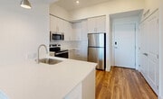 This well-appointed 2-bedroom, 2-bathroom unit at 27077 S Dixie Hwy in Homestead, FL offers a thoughtfully designed single-level layout with a clean, modern aesthetic. The open-concept kitchen serves as the heart of the unit, showcasing white shaker-style cabinetry, light quartz countertops, stainless steel appliances including a range, microwave, and refrigerator, and wood-look plank flooring that continues throughout the living areas. The living room is bright and inviting, with recessed lighting and a seamless flow from the kitchen. Both bedrooms are well-sized, featuring wood-look flooring, ceiling fans, and sliding glass doors that open to private balconies with sweeping open-sky views of the surrounding Homestead area. The primary bedroom includes a walk-in closet outfitted with wire shelving for generous storage. The two bathrooms each reflect a crisp, contemporary design — one features a soaking tub with shower combination, while the other offers a frameless sliding glass walk-in shower. Both baths are finished with white tile, modern vanities, and brushed nickel and gold-tone hardware. The overall ambiance is fresh, light-filled, and move-in ready, with a neutral palette that complements a variety of décor styles.