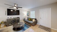 Located in Naples, Florida, this two-story, two-bedroom, three-bathroom home offers a well-organized layout spread across two floors. The main level features light-filled living spaces finished with neutral-toned walls and classic tile flooring throughout. The living room is a comfortable gathering area with a ceiling fan and natural light from a sizable window. Adjacent to it, the dining room is anchored by a stylish pendant chandelier and connects seamlessly to the kitchen via a convenient pass-through window. The kitchen is equipped with warm wood cabinetry, black appliances, recessed lighting, and ample counter space. A sliding glass door in the dining area opens to an outdoor view, bringing in natural light and easy outdoor access. The staircase, featuring a white balustrade, leads to the upper level where both bedrooms are located. The spacious primary bedroom offers carpeted flooring, a ceiling fan, and a well-sized closet. The second bedroom is similarly appointed with carpet, a ceiling fan, and natural light. Three bathrooms serve the home, including one with a full tub-shower combination accented by earth-toned tile. The overall ambiance is bright, clean, and welcoming — an ideal Naples retreat.