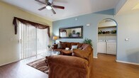 This single-floor residence offers a thoughtfully designed layout that maximizes comfort and functionality throughout. The living room serves as the heart of the home, featuring warm hardwood-style flooring, a ceiling fan, and a soothing blue accent wall adorned with a decorative mirror. A large sliding glass door floods the space with natural light while providing outdoor access, and an elegant arched passageway connects the living area to the rest of the home.

The galley-style kitchen is efficiently arranged with ample honey-toned cabinetry, generous counter space, a full suite of white appliances including a refrigerator, range, built-in microwave, and dishwasher, all set atop easy-care tile flooring. Adjacent to the kitchen, the dining area accommodates a round glass-top table and offers a refined yet relaxed atmosphere, complemented by soft wall tones and tasteful décor.

The bedroom is a serene retreat, complete with plush carpeting, a ceiling fan, large windows with decorative drapery, and a sizable closet. The full bathroom features warm-toned tile flooring, a tub-shower combination, and a wide vanity with generous storage beneath. A dedicated in-unit laundry area tucked neatly behind an arched alcove houses a full-size washer and dryer with overhead shelving for added storage convenience.