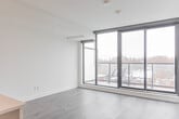 Located in Toronto's vibrant College Street neighbourhood, this well-appointed 2-bedroom, 2-bathroom unit offers a thoughtfully designed single-floor layout with modern finishes throughout. The open-concept kitchen anchors the living space, showcasing white cabinetry, quartz countertops, a large island with pendant lighting, stainless steel appliances including a French door refrigerator, electric range, built-in microwave, and dishwasher. Wide-plank hardwood flooring flows through the main living areas, and a glass sliding partition connects the kitchen to the living room, maximizing light and flexibility. The primary bedroom is a comfortable, well-proportioned room featuring black-framed windows that let in natural light, along with a generous built-in closet with sleek sliding doors and matte black hardware. The second bedroom similarly benefits from natural light and hardwood floors. Both bathrooms are finished in crisp white, with the main bath offering a soaker tub framed by white subway tile and tile flooring. The second bathroom features a white vanity with an integrated sink and a large mirror. A dedicated in-unit laundry room houses a stacked front-load washer and dryer. Recessed lighting and clean white walls throughout give the space a bright, contemporary feel.