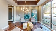 Located at 2000 Front St in Summerville, SC, this single-floor space seamlessly blends a professional conference environment with a sophisticated lounge aesthetic. The room is anchored by a substantial live-edge wood conference table surrounded by sleek, high-back upholstered chairs, making it well-suited for meetings and collaborative work sessions. A large window adjacent to the conference area allows natural light to pour in while offering views of the surrounding streetscape.

The lounge area features modern accent chairs with metal frames and natural tree stump side tables, adding an organic, earthy contrast to the contemporary design. Two large-scale abstract artworks in teal, blue, and yellow tones serve as striking focal points on the walls, contributing to the space's vibrant yet refined character.

Overhead, a bold circular chandelier with exposed Edison bulbs commands attention, complementing the tray ceiling detail highlighted by a deep, contrasting paint band. Recessed lighting throughout ensures consistent, warm illumination across both functional zones. Rich, dark hardwood flooring unifies the entire space, enhancing the overall warmth and sophistication. Floor-to-ceiling windows on multiple walls maximize daylight and maintain a strong visual connection to the outdoors, creating an open, inviting atmosphere ideal for both productive work and relaxed conversation.