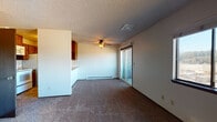 Located at 515 South Farr Road in Spokane, WA, unit E303 is a single-floor residence thoughtfully designed for comfortable everyday living. The open living and dining area serves as the heart of the unit, featuring wall-to-wall carpeting, a ceiling fan with light fixture, and a sliding glass door that opens to an outdoor balcony, filling the space with natural light. Baseboard heating runs along the perimeter, ensuring warmth throughout the cooler months. A pass-through counter with upper cabinetry connects the living area to the kitchen, creating a convenient and functional flow between spaces. The kitchen is appointed with warm wood-toned cabinetry, tile flooring, a double-basin sink, and includes a range with oven, built-in microwave, and refrigerator. A carpeted hallway lined with tall built-in storage leads to the bedroom and bathroom. The bedroom is a quiet, comfortably sized room with carpet, a baseboard heater, and a window offering natural light and outdoor views. The full bathroom features tile flooring, a wood-toned vanity with ample counter space, and a tub-shower combination. Textured ceilings are consistent throughout the unit, contributing to a cohesive, classic aesthetic.