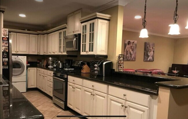Kitchen with granite countertops, refrigerator, washer, dryer, microwave, and range - 626 N Maria Ave