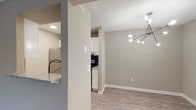 This upgraded one-bedroom, one-bathroom residence is thoughtfully designed across a single floor, offering a well-organized layout that balances comfort and functionality. The living room serves as a standout feature, boasting vaulted ceilings, plush carpeting, a ceiling fan, and a brick-surround fireplace. Large windows and a glass door flood the space with natural light while providing outdoor views, creating an inviting atmosphere. Adjacent to the living area, the dining space is distinguished by light wood-look flooring and a modern sputnik-style chandelier, adding a stylish focal point to the room. A pass-through window connects the dining area to the kitchen, which is fully equipped with white shaker cabinetry, granite-style countertops, a dark tile backsplash, and stainless steel appliances including a refrigerator, dishwasher, and range. The bedroom is generously sized with soft carpeting and a large window that allows ample natural light. The bathroom features a full-size soaking tub with shower combination, chrome fixtures, and granite-style countertops, maintaining the cohesive, upgraded aesthetic found throughout the residence. Neutral warm-gray tones unify each space.