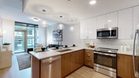 Located in the heart of Philadelphia's Rittenhouse Square neighborhood, this thoughtfully designed one-bedroom, one-bathroom residence offers a refined urban living experience across a single floor. Light hardwood flooring flows throughout, unifying each space with a warm, cohesive aesthetic.

The open-concept kitchen is a standout feature, showcasing two-tone cabinetry with white upper cabinets and rich walnut-finish lowers, a white quartz peninsula with bar seating, a subway tile backsplash, and a full suite of stainless steel appliances including a French door refrigerator. Statement globe pendant lights illuminate the space with a modern flair.

The living area is bright and airy, benefiting from expansive floor-to-ceiling windows that frame city views and flood the room with natural light. A bold teal accent wall adds a vibrant design element to the adjacent dining nook.

The bedroom continues the floor-to-ceiling window theme, offering urban views and a serene atmosphere complemented by a dark feature wall. A dedicated closet provides practical storage.

The full bathroom is elegantly appointed with a dual-sink floating vanity with white quartz countertops, backlit mirrors, tile flooring, and a soaking tub with shower combination, all finished in a clean, neutral palette.