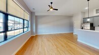 This well-appointed unit at 11 Stickney in Concord, NH offers a thoughtfully designed single-floor layout accommodating three bedrooms and one full bathroom. The open-concept living and kitchen area serves as the heart of the unit, where warm hardwood flooring, elevated ceilings, and large black-framed windows flood the space with natural light and urban views. A ceiling fan complements the generous proportions of the living room.

The kitchen is a standout feature, showcasing gray shaker-style cabinetry, quartz countertops with subtle veining, a white subway tile backsplash, stainless steel appliances, and pendant lighting. A matte black faucet adds a modern accent to the undermount sink.

The three bedrooms are carpeted and offer a quiet contrast to the main living areas. Each room includes closet storage, and the primary bedroom provides notable square footage. The hallway connects all rooms efficiently and includes additional utility access.

The bathroom is finished with large-format tile flooring, a gray vanity with a white quartz top, a tub-shower combination, and coordinating matte black fixtures throughout, maintaining a consistent modern aesthetic across the entire unit.