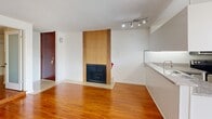 Located at 659 S Cloverdale Ave in the heart of Los Angeles, this single-floor unit offers a well-organized layout with a cohesive, clean aesthetic throughout. Rich hardwood flooring flows across the main living areas, providing warmth and continuity between spaces. The open living room is a standout, anchored by a floor-to-ceiling wood-surround fireplace and illuminated by a sleek track lighting fixture. A set of sliding glass doors connects the living area to a private balcony with outdoor seating, filling the space with natural light and views of lush greenery. The kitchen is efficiently designed with white cabinetry, granite countertops, a mosaic tile backsplash, and a full suite of stainless steel appliances including a double oven range, built-in microwave, refrigerator, and dishwasher. The bedroom features built-in shelving and wall-mounted lighting, offering practical storage solutions. A wall-mounted mini-split unit ensures climate comfort. The bathroom is finished with granite countertops, white cabinetry, tile flooring, recessed lighting, and a tub-shower combination. Textured ceilings are consistent throughout the unit, adding a classic Los Angeles residential character to this functional and well-appointed space.