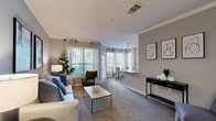 Located at 465 Elmcroft Blvd in Rockville, MD, this thoughtfully designed one-bedroom, one-bathroom residence offers a comfortable and functional single-floor layout. The open-concept living and dining area is bright and welcoming, featuring neutral carpet, crown molding, and large windows dressed with elegant curtains that flood the space with natural light and offer views of lush greenery. The dining area benefits from a charming bay-style window arrangement, creating an airy nook ideal for everyday meals. The galley-style kitchen is well-equipped, showcasing white shaker cabinetry, granite countertops, a grey subway tile backsplash, and wood-look flooring, offering ample counter and storage space. The generously sized bedroom features plush carpeting, a ceiling fan, natural light from a large window, and access to a walk-in closet. The bathroom is finished with a dual-sink vanity, white countertops, grey cabinetry, and wood-look tile flooring, providing a clean and functional space. A dedicated in-unit laundry area accommodates a full-sized washer and dryer with overhead shelving. The hallway connects all areas efficiently, rounding out a practical and polished floor plan.