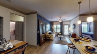 This well-appointed two-bedroom, two-bathroom residence in Spring, Texas offers a thoughtfully designed single-floor layout that balances comfort and style. The open-concept living area immediately draws attention with its striking navy blue accent wall, crown molding, and ceiling fan. Multiple windows and a glass patio door flood the space with natural light while providing outdoor views, creating an inviting and airy atmosphere.

The kitchen is a functional centerpiece, showcasing dark espresso cabinetry, granite countertops, a stainless steel refrigerator, and a peninsula with pendant lighting — ideal for both cooking and casual dining. Hardwood-style flooring flows throughout the main living areas, adding warmth and continuity.

The primary bedroom is generously sized with plush carpeting, a ceiling fan, and ample room for a sitting area. Its ensuite bathroom features dark cabinetry with granite counters, a glass-enclosed walk-in shower, hardwood-style flooring, and direct access to a walk-in closet. The second bedroom is equally comfortable, also carpeted with a ceiling fan. The second bathroom includes a full soaking tub and shower combination with tiled surround and granite countertops, maintaining the cohesive design aesthetic found throughout this well-crafted home.