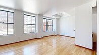 Located at 541 S Spring St, Unit 612, in the heart of downtown Los Angeles, this one-bedroom, one-bathroom residence offers a well-designed single-floor layout with a bright, open feel. The living area is expansive and airy, characterized by gleaming light hardwood floors and a row of large, industrial-style black-framed windows that flood the space with natural light and frame views of the surrounding downtown cityscape.

The kitchen is accessible via a half-wall pass-through counter finished with granite, creating a natural divide from the living area while maintaining openness. It features warm honey-toned wood cabinetry with glass-front upper cabinets, stone tile flooring, and stainless steel appliances including a full-size refrigerator.

The bedroom is a well-proportioned private retreat, also finished with hardwood floors and outfitted with large windows that offer urban views and ample natural light. Sliding frosted-glass and mirrored wood-framed doors add both style and practicality to the room's storage and layout.

The bathroom includes a tiled tub-shower combination with sliding glass doors, a wooden vanity, and tile flooring, providing a clean and functional design. Throughout the unit, white walls, warm wood tones, and consistent flooring create a cohesive and inviting urban living environment.