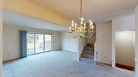 This multi-level home in Grand Blanc, Michigan is thoughtfully laid out across three floors, offering comfortable living with two bedrooms and three bathrooms. The entry level features a well-appointed kitchen with light oak cabinetry, a black electric range, stainless steel sink, and tile flooring bathed in natural light from a large window. Adjacent to the kitchen is a convenient half bathroom with warm oak vanity cabinetry and a well-lit mirror. The main living level showcases a spacious carpeted living room anchored by an elegant brass chandelier and sliding glass doors that open onto a private balcony with outdoor views. The dining area is highlighted by rich wood-paneled walls and a large picture window. The upper floor hosts two carpeted bedrooms, including a generously sized primary bedroom with dual windows that flood the room with natural light. Each full bathroom is finished with oak vanity cabinets, light tile flooring, and lighted mirrors. The lower level provides a basement and utility room, adding valuable storage and functional space. In-unit laundry further enhances everyday convenience. Multiple staircases and hallways connect the levels seamlessly throughout this well-organized home.
