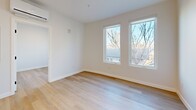 Located at 1722 Grove St in Denver's vibrant West Colfax neighborhood, this contemporary one-bedroom, one-bathroom unit offers a thoughtfully designed open-concept layout that maximizes every square foot. Light hardwood flooring flows seamlessly throughout, lending warmth and continuity to the space.

The kitchen serves as a central focal point, anchored by a sleek island with a white quartz countertop, an integrated sink with a matte black faucet, and dark cabinetry below. Upper cabinetry in a warm wood tone contrasts beautifully with the darker lower units, while stainless steel appliances — including a refrigerator, range, and microwave — complete the functional and stylish cooking space. A modern linear pendant light hangs above the island, adding a refined design touch.

The living area flows naturally from the kitchen, bathed in natural light from dual windows that frame outdoor tree views, creating a bright and airy atmosphere. The bedroom is a calm, well-lit retreat, also featuring dual windows with neighborhood views and clean white walls.

The bathroom is finished in crisp white with a full soaking tub and shower combination, complemented by matte black fixtures for a contemporary edge. Additional conveniences include an in-unit laundry area, a closet, and a hallway connecting all spaces efficiently. The unit also features a wall-mounted mini-split system for climate control.