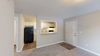 This single-floor residence offers a thoughtfully designed layout that balances functionality and comfort throughout its key living spaces. The living area is generously sized, finished with soft wall-to-wall carpeting and neutral warm-toned walls that create a welcoming atmosphere. A paneled entry door provides direct access to the space, and natural light filters in through a window in the bedroom, enhancing the overall brightness of the unit.

The kitchen is efficiently laid out in a galley style, featuring white shaker-style cabinetry, light granite-look countertops, a stainless steel sink, a black electric range, and a black dishwasher and refrigerator. A pass-through window with a breakfast bar counter opens the kitchen directly to the living area, promoting an open and connected feel between the two spaces. Wood-look flooring runs throughout the kitchen, adding warmth and durability.

The bedroom is a comfortable, carpeted room equipped with a ceiling fan and a window that allows for natural light and ventilation. The full bathroom includes a white vanity with a light stone-top countertop, an undermount sink with brushed nickel fixtures, a lighted mirror, and a combined tub and shower enclosure. Wood-look flooring in the bathroom complements the clean, bright finishes found throughout the rest of the space.