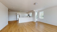 Located at 801 SW Bradbury Dr in Bend, Oregon, this single-floor unit offers a clean, contemporary design throughout. The open-concept living and dining area is anchored by warm light hardwood flooring that extends through the main living spaces, creating a bright and cohesive atmosphere. Large windows allow abundant natural light to fill the rooms, with views of surrounding greenery enhancing the sense of connection to the outdoors. A wall-mounted mini-split system provides efficient heating and cooling in both the living area and bedroom.

The kitchen is thoughtfully designed with white shaker cabinetry, light quartz countertops, a peninsula breakfast bar, and a full suite of stainless steel appliances including an electric range, over-the-range microwave, refrigerator, and dishwasher. A window above the range brings in additional natural light.

The bedroom features plush neutral carpet and its own wall-mounted mini-split unit, ensuring year-round comfort. The bathroom includes a white vanity with quartz countertop, a large mirror, and a soaking tub with shower combination. A second bathroom provides additional convenience with matching finishes consistent throughout the unit. Recessed lighting and flush-mount fixtures complete the modern, understated aesthetic.