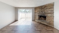 This two-floor residence offers a thoughtfully designed layout with a mix of hardwood-style and carpeted flooring across its living spaces. The main living area serves as the centerpiece of the home, highlighted by a striking floor-to-ceiling stacked stone fireplace that adds rustic character and warmth. Large sliding glass doors flood the space with natural light and provide access to an outdoor area, creating a seamless indoor-outdoor connection.

The kitchen is well-appointed with dark cabinetry, light speckled countertops, and stainless steel appliances including a dishwasher and range with overhead ventilation. A wide window above the counter brings in additional natural light, complementing the warm hardwood-style flooring that extends through the main level.

The bedrooms are carpeted for comfort and feature neutral gray walls, textured ceilings, and built-in closets. Windows with vertical blinds allow natural light to filter in while maintaining privacy. The bathroom is clean and functional, featuring dark cabinetry with matching countertops, light vinyl plank flooring, and brushed nickel hardware accents. Throughout the home, a consistent neutral color palette and practical finishes create a cohesive and inviting atmosphere.