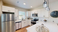Located in Goodyear, Arizona, this single-story 4-bedroom, 2-bathroom home offers a thoughtfully designed open-concept layout with modern finishes throughout. The kitchen is a standout feature, showcasing crisp white shaker cabinets, a subway tile backsplash, quartz countertops, and stainless steel appliances. A spacious island with seating for multiple guests flows naturally into the dining area, which is bright and open with warm wood-look flooring. The living room offers a comfortable gathering space with a ceiling fan, natural light from multiple windows, and a welcoming, neutral color palette. Each of the four bedrooms is well-proportioned, with the primary bedroom featuring a ceiling fan, a walk-in closet with wire shelving, and a window with outdoor views of mature landscaping. Both bathrooms are finished with white vanity cabinetry, black hardware accents, and clean, contemporary fixtures. The hallways are lined with recessed lighting and tasteful décor niches, contributing to a cohesive and polished interior aesthetic. Warm-toned walls and consistent wood-look flooring run throughout the home, creating a unified and inviting atmosphere well-suited to the Arizona lifestyle.