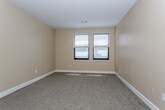 This single-floor unit offers a well-organized layout designed for comfortable everyday living. The open living area is finished with plush neutral carpeting and crowned with elegant crown molding, complemented by a pendant light fixture and windows fitted with horizontal blinds that allow natural light to fill the space. The kitchen is designed in a galley configuration, featuring dark espresso cabinetry, granite-style countertops, wood-look tile flooring, and stainless steel appliances including a refrigerator and dishwasher, creating a functional and stylish cooking environment.

The bedrooms are generously proportioned, each finished with soft carpeting and warm beige walls. One bedroom includes access to a walk-in closet, providing ample storage. Both bathrooms echo a consistent design aesthetic, showcasing wood-look tile flooring, dark vanity cabinetry with granite countertops, a tub-shower combination with white tile surround, and chrome fixtures.

A dedicated laundry area houses a full-size GE top-load washer and dryer set, along with overhead wire shelving for additional storage. The unit's cohesive neutral palette, quality finishes throughout, and practical layout make it a thoroughly functional and inviting living space.